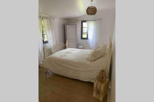 - une chambre avec un lit doté de draps blancs et de fenêtres dans l'établissement La Petite Maison au bord de l’étang, à Chirac