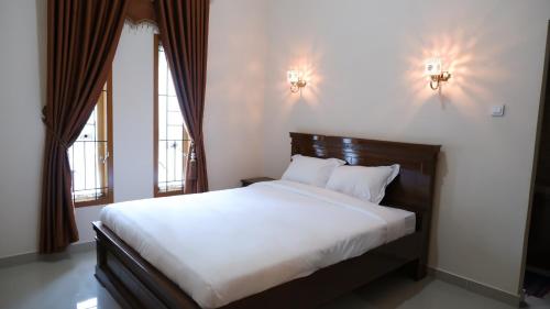 1 Schlafzimmer mit einem Bett mit weißer Bettwäsche und 2 Fenstern in der Unterkunft Baringin Anam Guest House Syariah in Baso