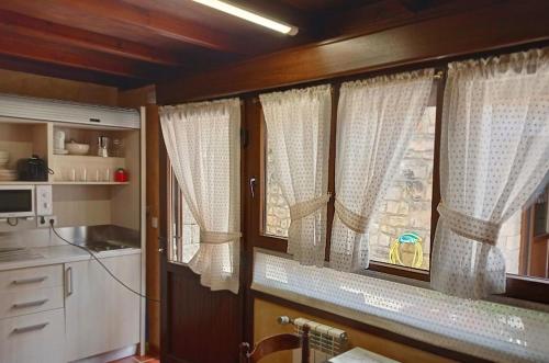 cocina con cortinas blancas y ventana en la cocina en Hotel Arenas de Cabrales- apartamentos, en Arenas de Cabrales