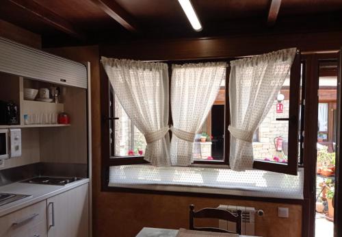 a kitchen with a window with curtains on it at Hotel Arenas de Cabrales- apartamentos in Arenas de Cabrales