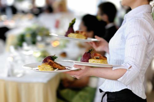 a woman holding two plates of food on plates at Hotel Landgasthof Sonne in Mahlberg