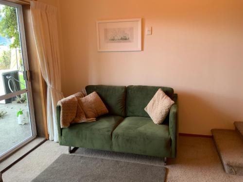 a green couch in a living room with a window at Brook House B&B & Cottages in Kaikoura