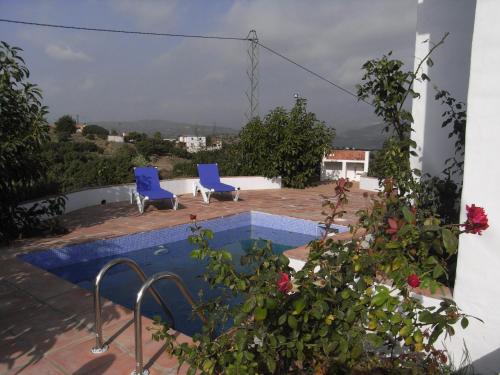 a swimming pool with two blue chairs on a patio at La Casilla del Pastor in Vélez-Málaga