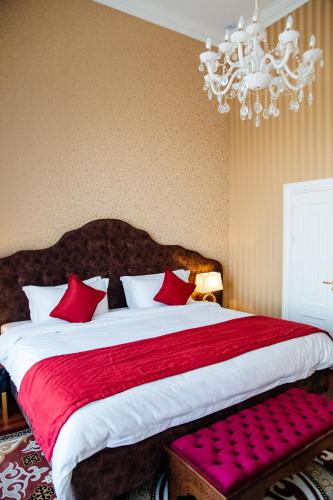 a bedroom with a large bed with red pillows and a chandelier at Boutique Hotel Silk Way in Türkistan