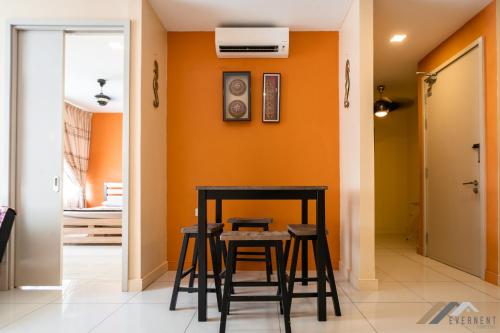 a table and stools in a room with an orange wall at Marina Times Square Homestay by Evernent in Miri