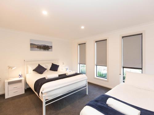 a white bedroom with two beds and windows at Jindalee 1 11 Twynam Street in Jindabyne