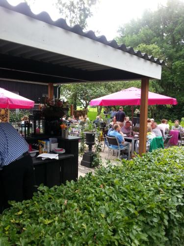 a group of people sitting at tables under umbrellas at Hotel Boerderij Restaurant De Gloepe in Diffelen