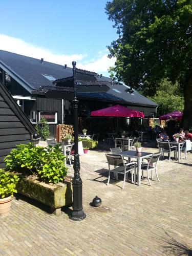 a patio with tables and chairs and an umbrella at Hotel Boerderij Restaurant De Gloepe in Diffelen