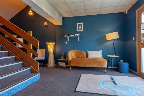 - un salon avec un canapé et un mur bleu dans l'établissement The Originals City, Hôtel Limoges Sud Feytiat, à Feytiat