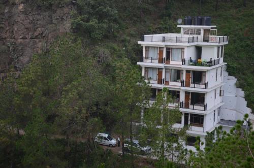 a white building on the side of a mountain at Hotel The Paal in Shimla