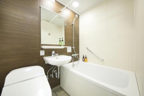 y baño con aseo blanco y lavamanos. en Hotel Nagano Avenue, en Nagano