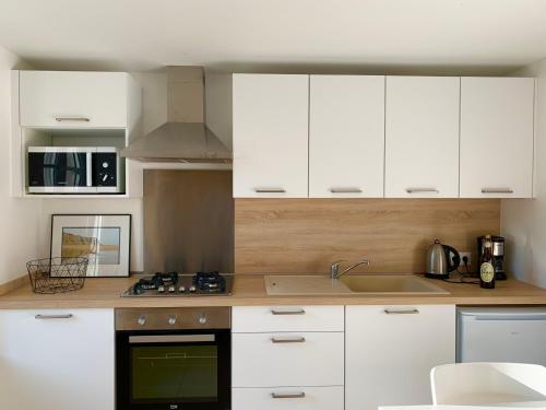 une cuisine avec des armoires blanches et un évier dans l'établissement Ferme de la Haute-Escalles, à Escalles