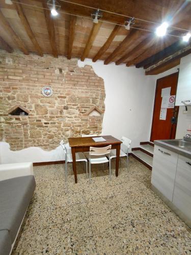 a kitchen with a table and chairs and a brick wall at Casa Vicolo delle Chiavi in Poggibonsi