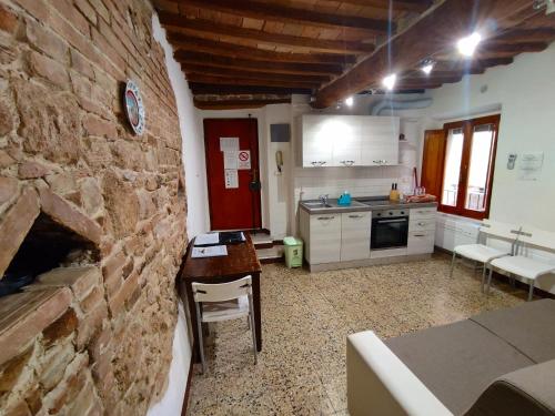 a kitchen with a stone wall and a table and chairs at Casa Vicolo delle Chiavi in Poggibonsi