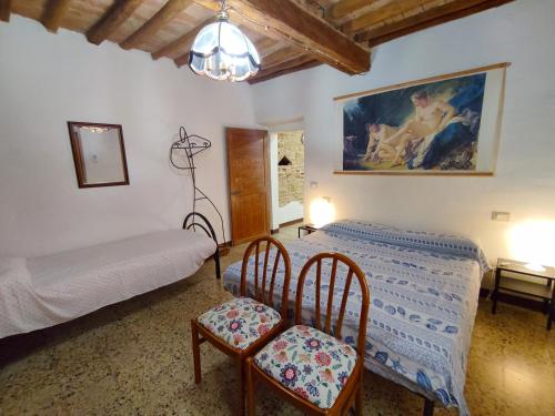 a bedroom with a bed and two chairs and a painting at Casa Vicolo delle Chiavi in Poggibonsi