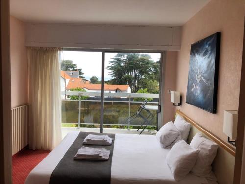 a hotel room with a bed and a large window at Hotel Particulier LE ROCHER DES MARAIS "Proximité Plage & Vue mer pour certains hébergements" in Pornic