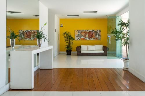 a living room with yellow walls and a couch at Bora Bora Resort Barra da Tijuca in Rio de Janeiro