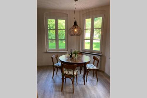 ein Esszimmer mit einem Tisch, Stühlen und Fenstern in der Unterkunft Dinkel Haus an der Mosel in Traben-Trarbach