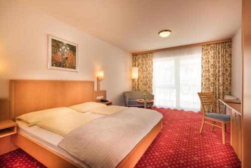 a hotel room with a large bed and a desk at Aktiv- & Gesundheitsresort das GXUND - Thermeneintritt inklusive in Bad Hofgastein