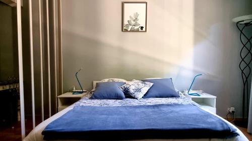 een slaapkamer met een bed met blauwe lakens en kussens bij Studios du Rempart in Avignon