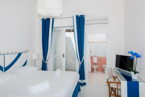 a white and blue bedroom with a bed and a tv at Laurito Beach Cucina & Camere in Positano