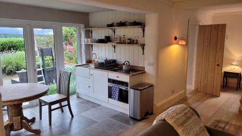 a kitchen with a stove and a table with a table at Ty Farm Retreat - Farmhouse Studio - Mountain View in Eglwys-Fâch