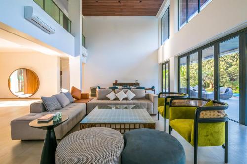 a living room with a couch and a table and chairs at Reflection House by StayVista with Pool, Terrace bar, Indoor games & Exquisite interiors in a nutshell in Alibaug