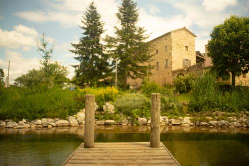 un quai en bois au milieu d'un lac avec un bâtiment dans l'établissement Mas Héritage, 1455 route de Balbiac, à Rosières