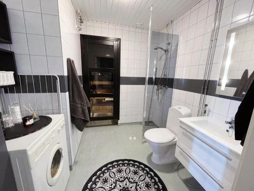 a bathroom with a sink and a toilet and a tub at Apartment Sanctus Nicolaus with sauna in Rovaniemi