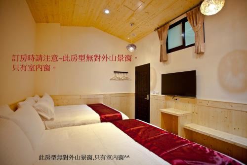 a hotel room with two beds and a television at Sin Ging Hong Resort in Lugu Lake