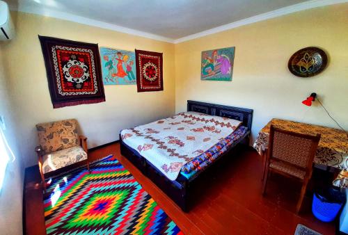 1 dormitorio con 1 cama, 1 silla y 1 alfombra en Art Guest House USTO, en Bukhara
