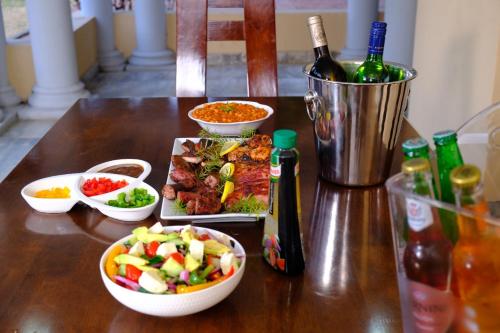 a table with plates of food and bottles of wine at Selina Airport Lodge #Emzini in Kempton Park
