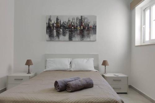 a bedroom with a bed with a painting on the wall at Brand new 3 bedroom Apartment close to the sea in Il-Gżira