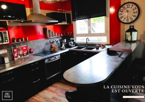 a kitchen with red walls and a large clock on the wall at Chez Patou in Laval