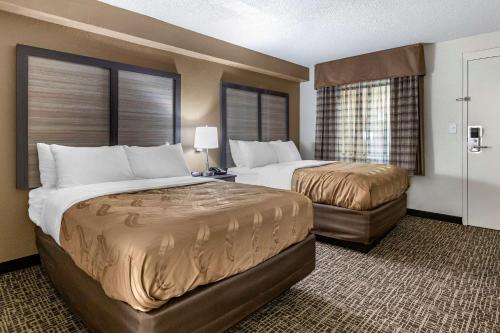 a hotel room with two beds and two windows at Quality Inn & Suites Spring Lake - Fayetteville Near Fort Liberty in Spring Lake