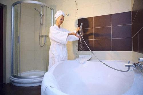 a woman standing in a bathroom with a shower at Residence Troya in Samara