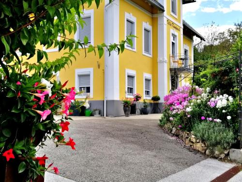 a yellow house with flowers in front of it at Villa Komposch - adults only in Reifnitz