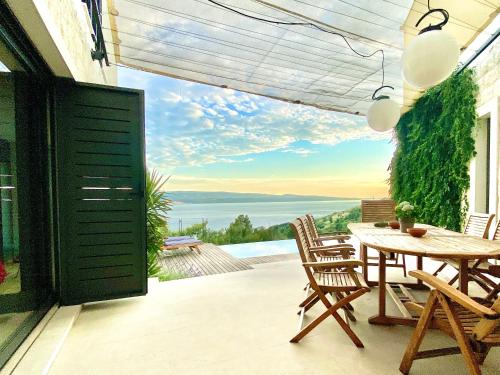 a patio with a table and chairs and a view of the water at Villa FORTE-Exclusive location with fantastic seaview & infinity pool - up to 8 Pax in Mimice
