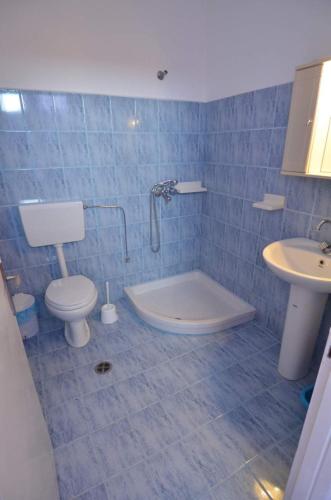 a blue tiled bathroom with a toilet and a sink at Marianthi Studios Stegna in Archangelos