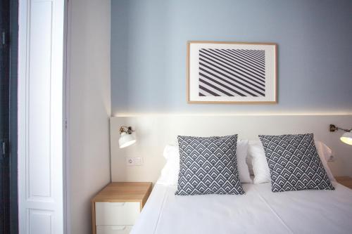 a bedroom with a white bed with two pillows at Gran Central Suites in Madrid