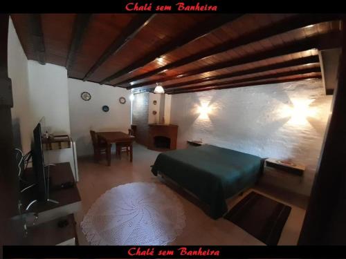 a bedroom with a green bed and a table at Latvia Chalés in Monte Verde