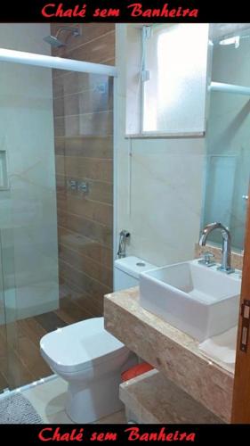 a bathroom with a toilet and a sink and a mirror at Latvia Chalés in Monte Verde