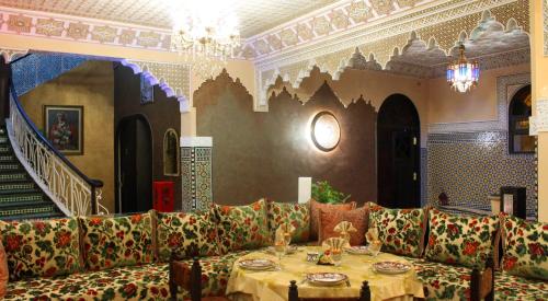 a room with a table and couches and a staircase at Collier De La Colombe in Meknès