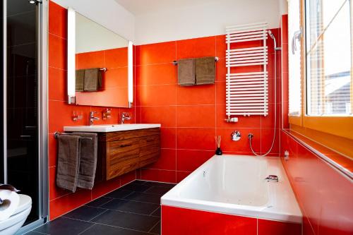 an orange bathroom with a tub and a sink at Valletta in Arosa