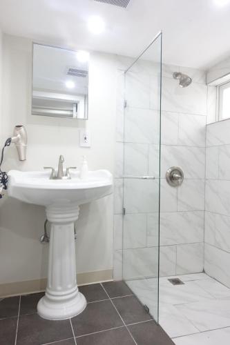 La salle de bains blanche est pourvue d'un lavabo et d'une douche. dans l'établissement Best EWR Airport Apt-Hot Tub-Free Parking, à Hillside