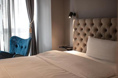 Nikii City Hotel في ليفركوزن: سرير وكرسي ازرق بجانب نافذه