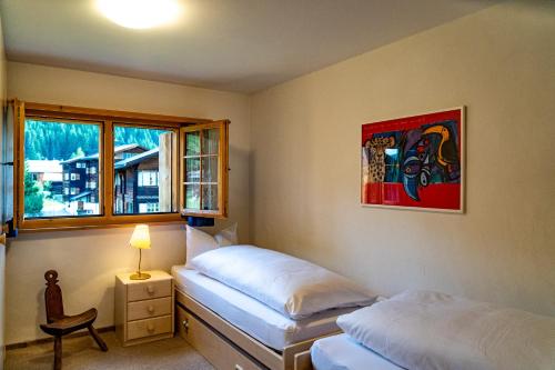 a bedroom with two beds and a chair and a window at Kulmwiesli in Arosa