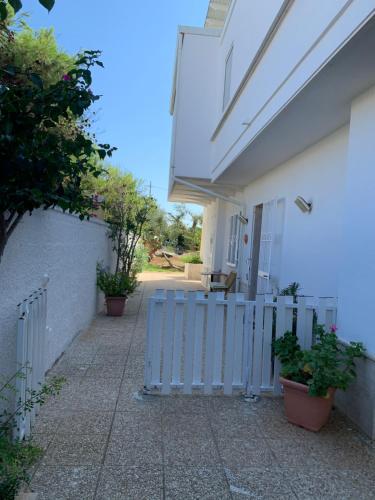 a white house with a blue fence and plants at Mansarda sul Mare in Torre Lapillo