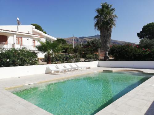 a swimming pool with chairs and a house at Il Volo Dei Gabbiani in Scopello