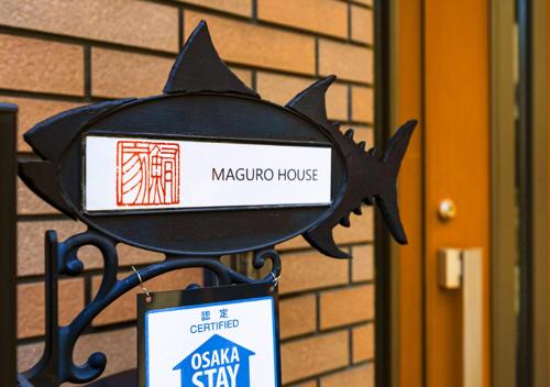 a sign for a maruca house with a shark head on it at Maguro House in Osaka